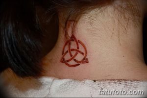 Фото тату: небольшой кельтский узел, выполненный в красноватых тонах, расположен на затылке. Минималистичный рисунок для ценителей кельтской символики.