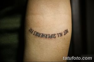 Фото текстовой татуировки на руке: надпись "NOT ALL SUPERHEROES FLY". Черно-белый рисунок, выполненный простым шрифтом.