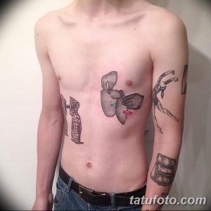 Фото тату на теле мужчины с сюрреалистичным рисунком: лицо, частично закрытое рукой, и абстрактные фигуры. Черно-белая татуировка, выполненная в графическом стиле.