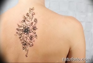 Фото тату мехенди на плече девушки. Детализированный цветочный узор, выполненный в технике росписи хной, украшает верхнюю часть плеча и спину.