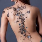 Фото тату мехенди на спине девушки, украшенного сверкающими кристаллами. Сложный узор из хны тянется вдоль позвоночника, создавая эффект роскошного украшения.