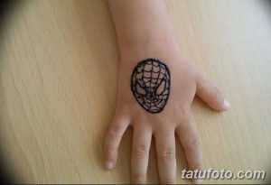 Фото татуировки Человека-паука на детской руке. Черный рисунок татуировки с изображением маски супергероя.
