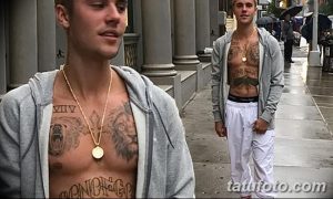 Фотография Джастина Бибера с татуировками на груди, руках и шее. Видны изображения медведя, льва и другие символы.