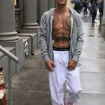 Фото тату: Джастин Бибер демонстрирует татуировки на груди и руках, одетый в куртку и белую футболку.
