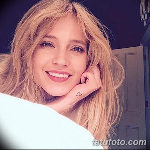 Фотография певицы Глюкозы с татуировкой в виде сердечка на запястье. Певица улыбается в камеру.