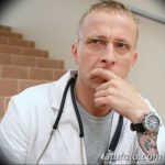 Фотография Михаила Горшенёва в медицинском халате с татуировками на руке, демонстрирующая его многогранную личность и провокационный стиль.