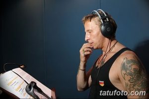 Фотография Игоря Талькова в наушниках, с татуировками на руке, за работой над текстом.