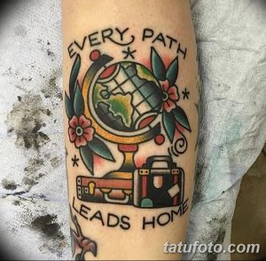 Фото тату с изображением глобуса, чемодана и надписью 'Every path leads home'. Стиль олд скул, яркие цвета и четкие линии.