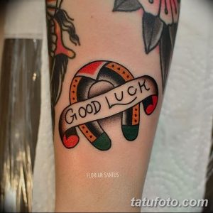 Фото татуировки подковы с надписью "Good Luck", выполненной в ярком стиле олд скул на руке.