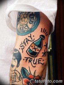 Фото татуировки бутылки с вытекающей жидкостью и надписью 'Stay True', выполненной в ярком стиле олд скул с использованием синих и красных цветов.