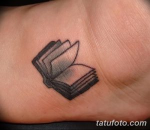 Фото миниатюрной татуировки на ладони с изображением открытой книги. Черно-белый рисунок татуировки в минималистичном стиле.