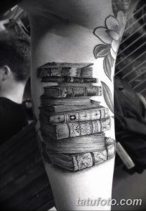 Фото тату с изображением стопки старинных книг на предплечье, выполненное в реалистичном стиле с использованием черных и серых оттенков.