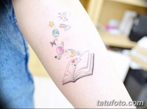 Фото тату: цветная татуировка на руке с изображением открытой книги, из которой вылетают планеты, звезды и самолеты. Символизирует мечты, воображение и безграничные возможности.