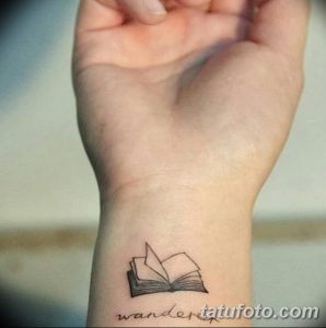 Фото тату с изображением открытой книги и надписью 'wander' на запястье, выполненной в стиле минимализм.
