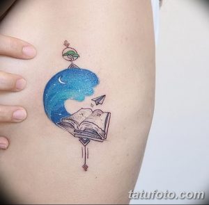 Фото тату: цветная татуировка на бедре с изображением раскрытой книги, из которой вылетает бумажный самолет. Нежный стиль, акварельные переходы.
