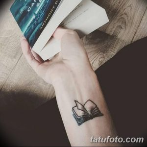 Фото тату: небольшая, минималистичная татуировка с изображением открытой книги на запястье. Черно-белый рисунок, четкие линии.