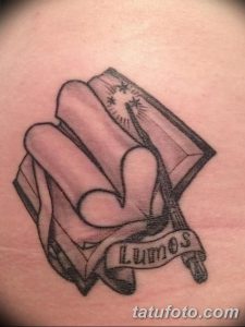 Фото тату на руке: Открытая книга с заклинанием 'Lumos' из Гарри Поттера. Черно-серый стиль, детализированная проработка.