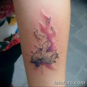Фото акварельной татуировки на руке, изображающей открытую книгу с вылетающими страницами. Нежные цвета и плавные переходы создают эффект легкости.