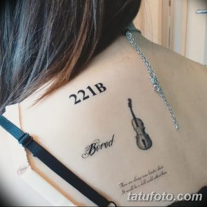 Фото оригинальной татуировки скрипки с надписью "221B" и словом "Bored" на лопатке. Необычный рисунок татуировки с элементами текста.