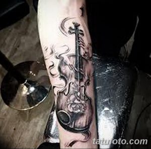 Фото татуировки скрипки, выполненной в стиле blackwork с добавлением элементов дыма и тумана. Черно-белый рисунок татуировки с высокой детализацией.