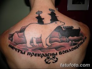 Фото тату на спине с изображением белого медведя, окруженного надписью на русском языке и морскими символами. Рисунок выполнен в черно-белой гамме.