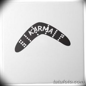 Фото тату: бумеранг с надписью "Karma" внутри. Черно-белое изображение, простой дизайн, символическое значение.
