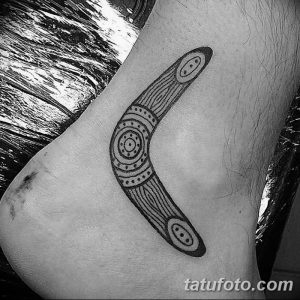 Фото тату на лодыжке: черный бумеранг с геометрическим узором в стиле blackwork.