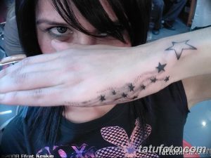 Фото татуировки на запястье с изображением дорожки из маленьких серых звезд, рассыпающихся от запястья к локтю. Дизайн выполнен в технике акварели.