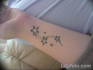 Фото минималистичной татуировки на запястье: цепочка из маленьких звезд, расположенных в виде дуги. Тонкие линии, нежный дизайн.