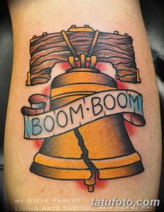 Фото тату колокола на предплечье в стиле олдскул с надписью 'BOOM-BOOM'. Яркие цвета и четкие контуры.