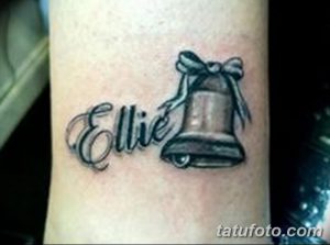 Фото татуировки колокола с именем "Ellie" и бантом на руке. Простой и элегантный рисунок татуировки в черно-серых тонах.