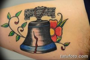 Фото татуировки в стиле олдскул с изображением колокола и красной розы на руке. Яркий и красочный рисунок татуировки в традиционном стиле.