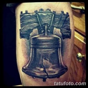 Фото реалистичной татуировки колокола Свободы, расположенной на предплечье. Детализированное изображение с тенями и текстурами, создающее эффект объема.