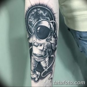 Фото реалистичной татуировки космонавта, парящего в космосе на фоне Луны. Детализированный рисунок татуировки выполнен в черно-серых тонах.