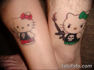 Фото тату двух Hello Kitty с оружием на предплечьях. Одна в розовом, другая в зеленом. Необычный и забавный дизайн для тех, кто любит контрасты.