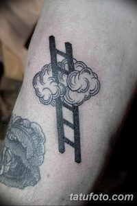 Черно-серая татуировка на руке, изображающая лестницу, уходящую в облака. Изящный рисунок с мягкими линиями.