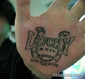 Фото тату: Татуировка подковы с надписью 'Lucky Bail Bonds' и номером телефона на ладони. Необычный и запоминающийся дизайн.