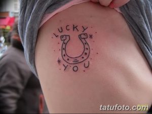 Фото тату: Минималистичная татуировка подковы с надписью 'Lucky You' и звездочками на боку. Небольшой и символичный рисунок.