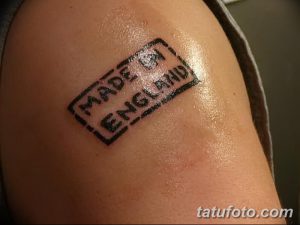 Фото тату в виде почтового штампа с надписью "Made in England". Черно-белый рисунок татуировки на плече. Минималистичный эскиз тату.