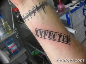 Фото тату надписи 'INFECTED' черным цветом на мужском запястье. Стиль татуировки - леттеринг, четкие контуры, минимализм.
