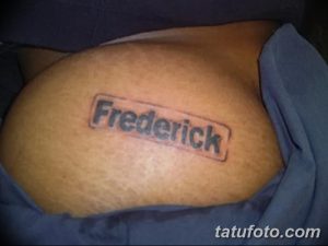 Фото простой татуировки на руке с именем 'Frederick', заключенным в рамку. Черно-белый рисунок, выполненный четким шрифтом.