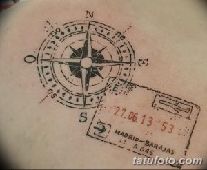 Фото минималистичной татуировки на руке с изображением компаса и штампа путешествия. Черно-белый рисунок, выполненный тонкими линиями.