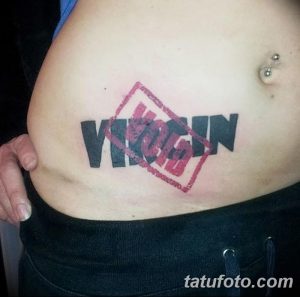 Фото тату на животе: надпись 'VIRGIN' перечеркнута красным крестом. Провокационный и необычный рисунок татуировки.