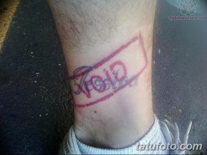 Фото тату на лодыжке: надпись 'VOID' в красной прямоугольной рамке. Простой, минималистичный рисунок татуировки, выполненный в красном и черном цветах.