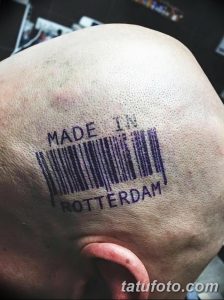 Фото татуировки штрихкода с надписью 'Made in Rotterdam' на плече. Черно-белый рисунок тату, выполненный в стиле минимализм.