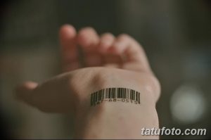 Фото татуировки штрих-кода с цифрами на запястье руки. Черный рисунок татуировки выглядит минималистично и современно.