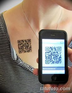 Фото татуировки QR-кода на груди женщины, с изображением смартфона, сканирующего код. Современный стиль, минимализм, технологичность.