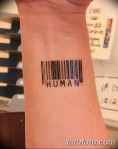 Фото тату штрихкода с надписью 'HUMAN' на запястье. Черный рисунок татуировки, минималистичный стиль, акцент на человеческой сущности.