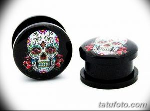 Фото плагов для ушей с изображением черепов в стиле сахарных черепов (calavera) и красных роз. Мрачный и стильный аксессуар.