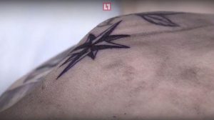 Фотография черно-серой татуировки в виде морской звезды на плече. Простые линии, минималистичный дизайн, небольшая татуировка.